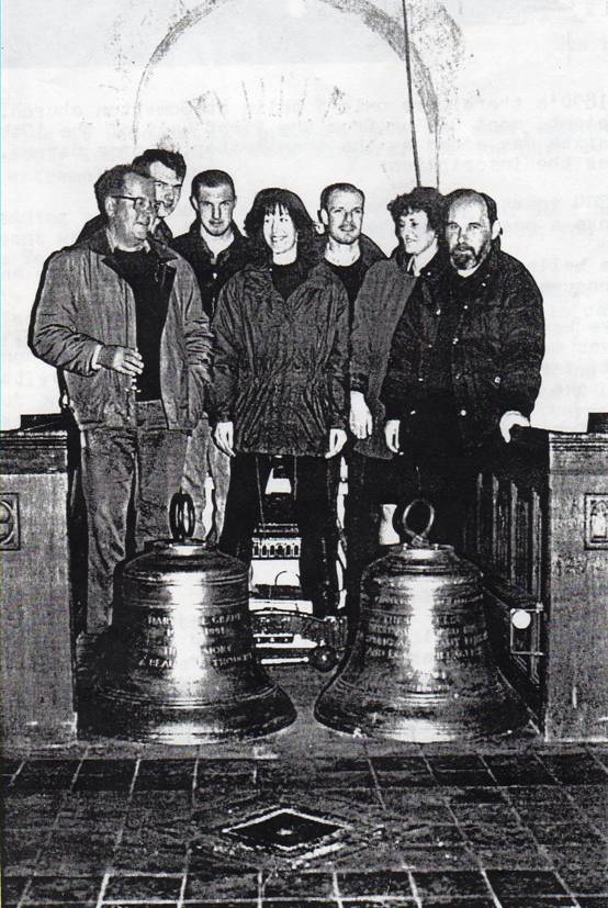 Seven bell ringers standing behind two new bells